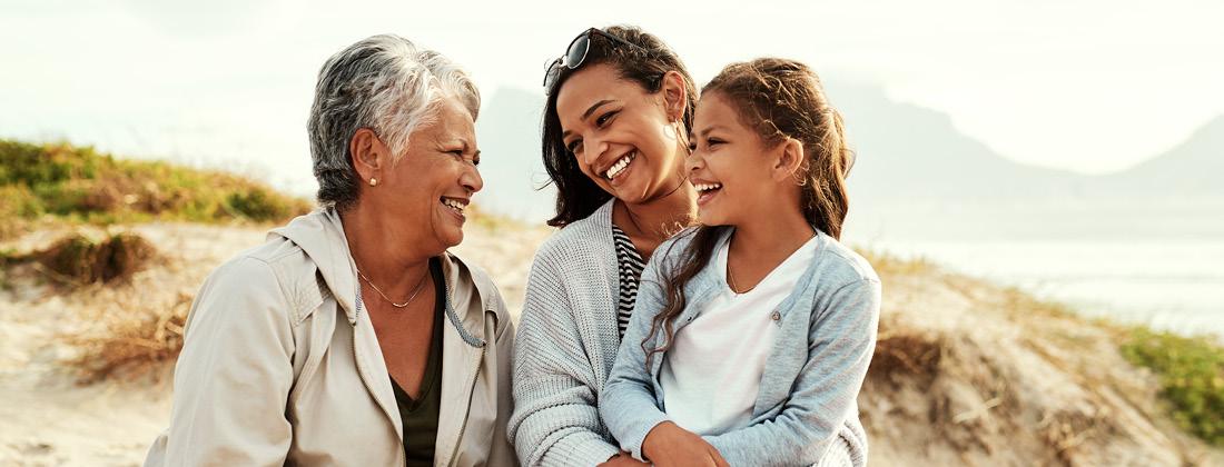 Grandmother with mother and child on beach smiling happy