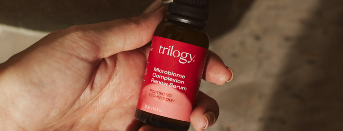 Hand holding a bottle of Trilogy Microbiome Complexion Renew Serum