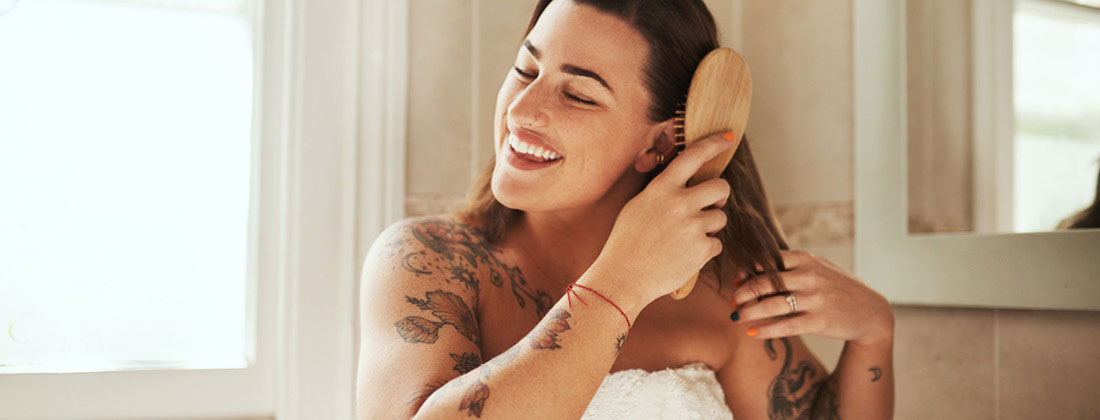 Woman happily brushes through wet hair with comb