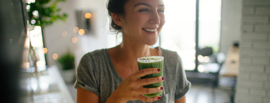 Woman smiles with cold healthy beverage in hand
