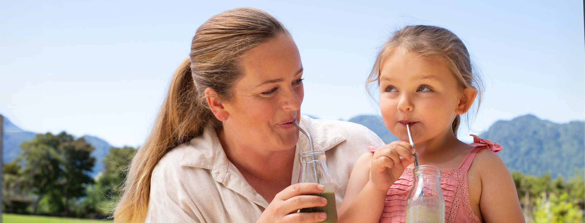 mother and daughter enjoying a nourishing smoothie together outdoors