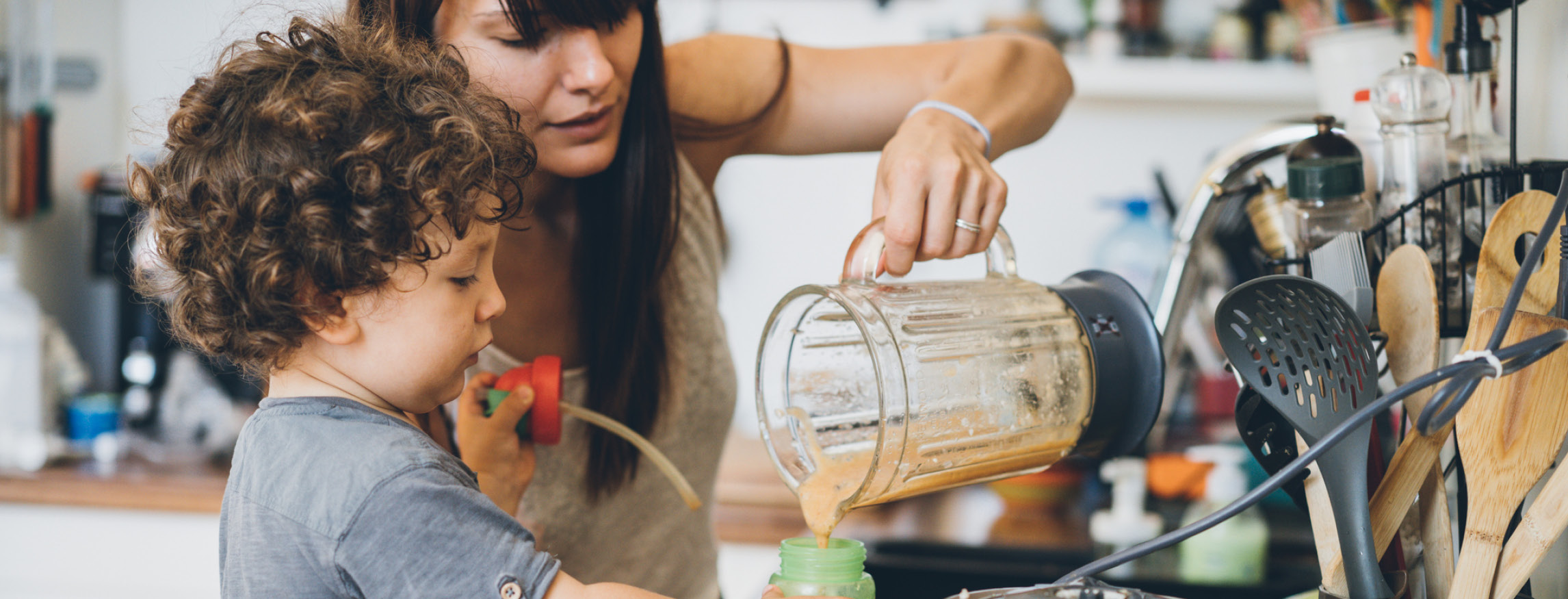 Mother and young child making a smoothie together in the kitchen