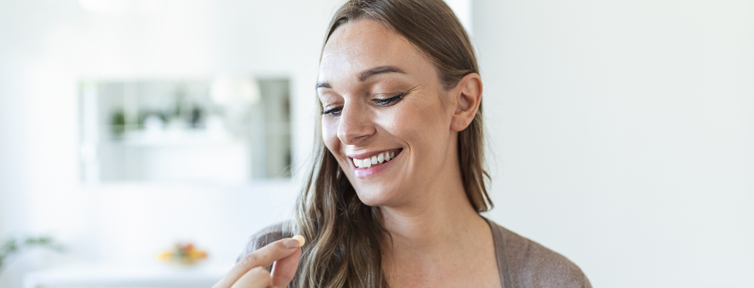 smiling woman taking a magnesium supplement