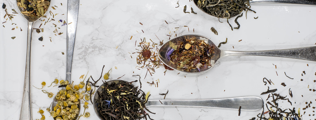 Spoonfuls of dried herbs for stress and immune health on a plain background