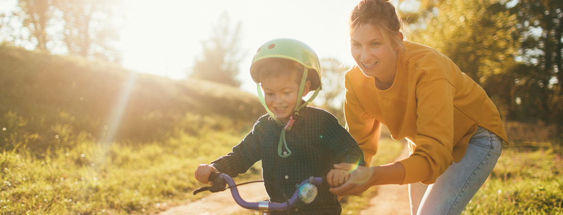 woman helping child ride a bike building healthy kids 