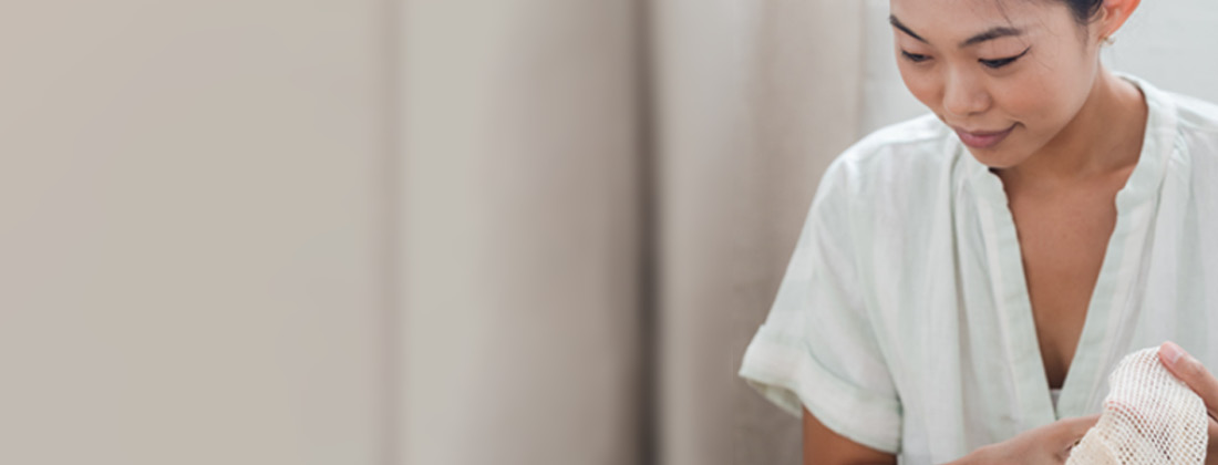 Woman Wearing White Shirt Places Item Into Reusable Bag 